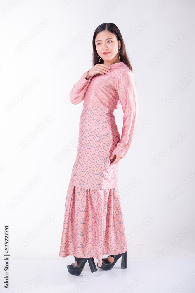 A portrait of a young Indonesian lady looking beautiful wearing traditional Malaysian or Indonesian wear isolated on a white background. Idul Fitri fashion concept. A portrait of a young Indonesian lady looking beautiful wearing traditional Malaysian or Indonesian wear isolated on a white background. Idul Fitri fashion concept.