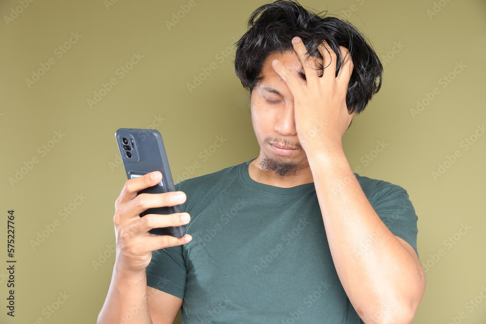 Asian male in messy hair with stress emotion over green background. Asian male in messy hair with stress emotion over green background.