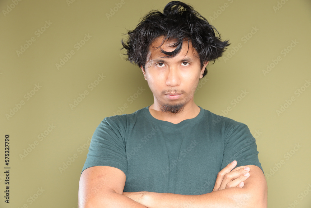 Asian male in messy hair with stress emotion over green background. Asian male in messy hair with stress emotion over green background.