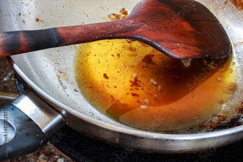 Fotografie Pouring used cooking oil from frying pan into colander.