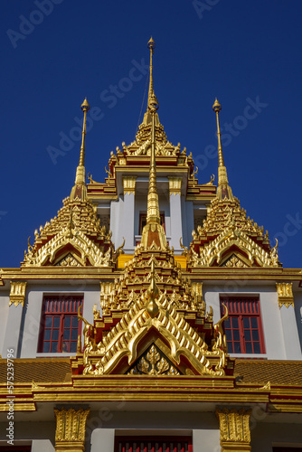 Looking up at the detail of the golden spires against blue sky of Loha Prasat, Iron castle or iron monestary officially called  Wat Ratchanatdaram Worawihan in Bangkok, Thailand.