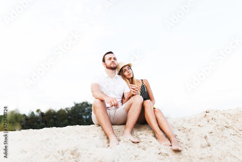 young couple in love are sitting on a sandy beach on vacation