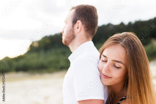 man and a woman are hugging on a sandy beach in summer © Cavan