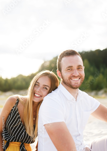 young couple in love are sitting on a sandy beach on vacation