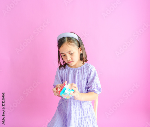 фотографія Pretty little girl sitting on a chair trying to solve a Rubik's cube