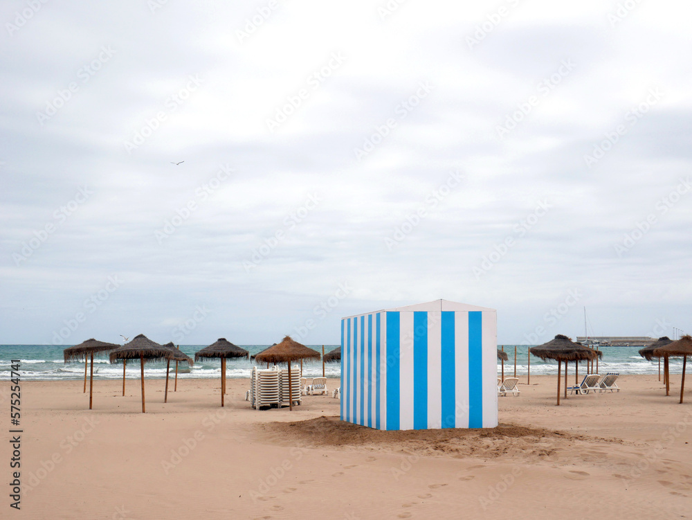 Quiet and relaxing beach with umbrellas striped blue and white ticket office