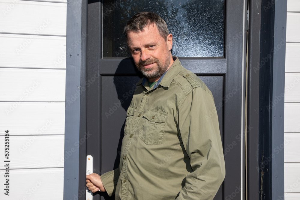 handsome smiling man bearded posing front grey door home property outdoors handsome smiling man bearded posing front grey door home property outdoors