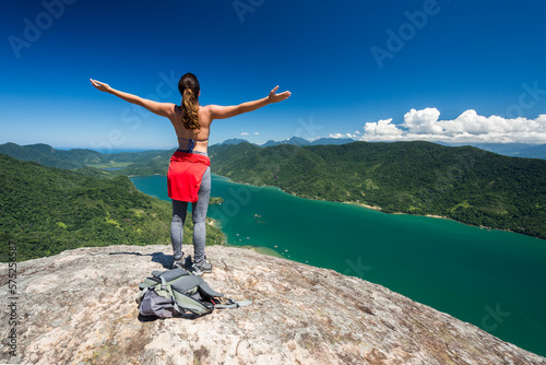 Young woman on mountain with arms outstretched, Saco do Mamangua, Paraty, Costa Verde, Brazil photo