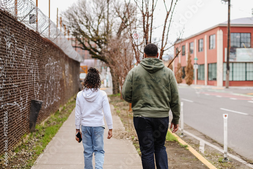 Black Father and son walking downtown on sidewalk in Portland, OR photo