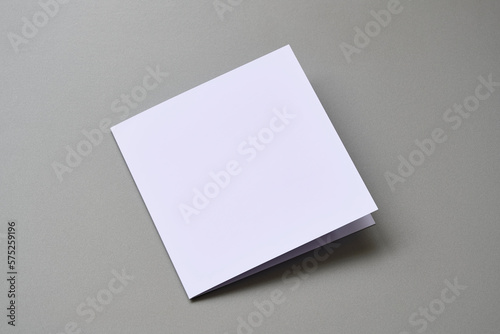 Laying blank closed empty square greeting card mock up on grey background. For use as a Christmas, birthday, wedding or celebration background template.