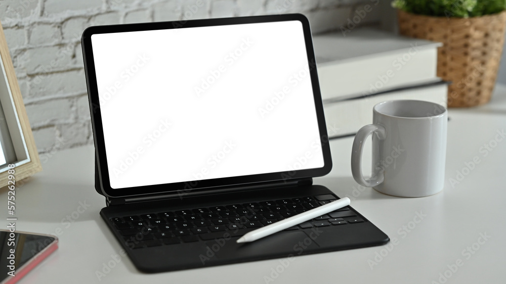 Digital tablet with wireless keyboard, coffee cup and supplies on white working desk. Blank screen for advertise webpage or text Digital tablet with wireless keyboard, coffee cup and supplies on white working desk. Blank screen for advertise webpage or text