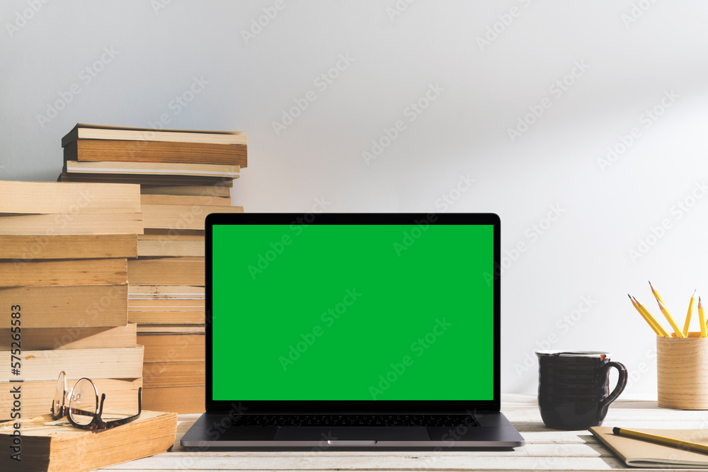 Chroma key green screen laptop on table with pile of books on the table Chroma key green screen laptop on table with pile of books on the table