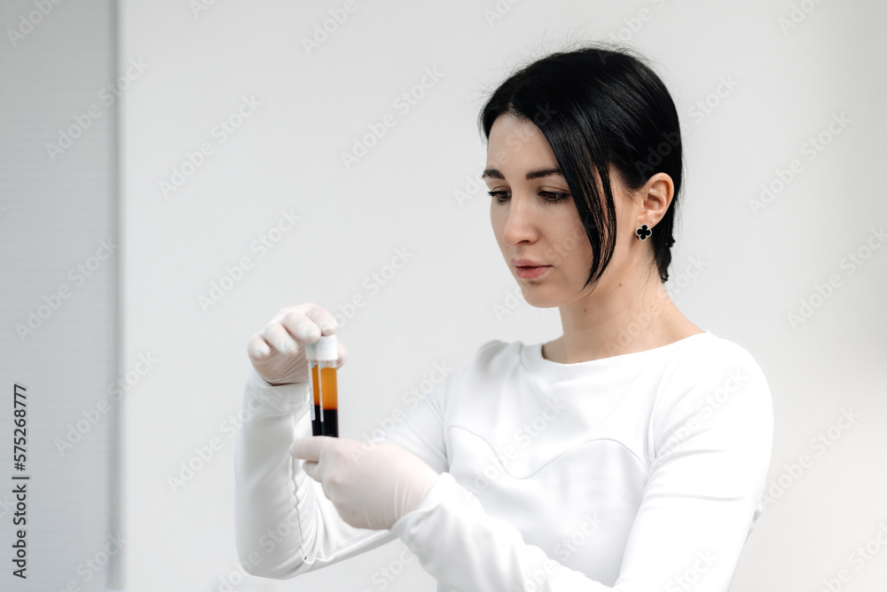 Doctor-cosmetologist in white coat and blue gloves demonstrates blood collection tube with centrifuged blood - separated platelet rich plasma. PRP footage 3 of 6 Doctor-cosmetologist in white coat and blue gloves demonstrates blood collection tube with centrifuged blood - separated platelet rich plasma. PRP footage 3 of 6