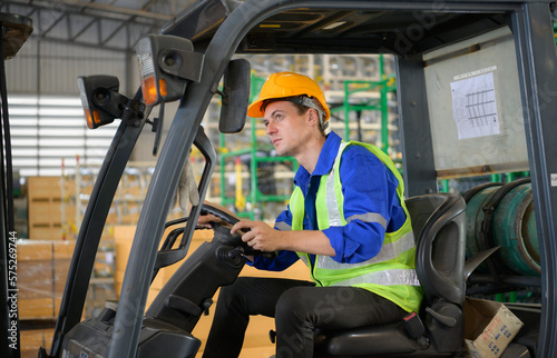 Worker in auto parts warehouse use a forklift to work to bring the box of auto parts into the storage shelf of the warehouse waiting for delivery to the car assembly line
