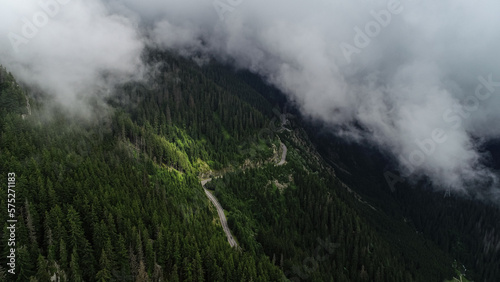 Amazing roads of the world. Aerial view over Transfagarasan landmark road of Romania, waving through the landscape of Fagaras Mountains in a cloudy day with fog coming out of the forest.
