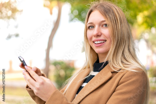 Young pretty blonde woman at outdoors sending a message or email with the mobile
