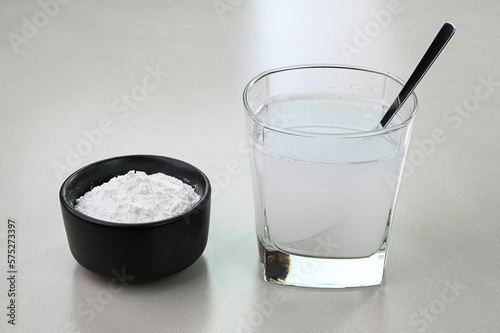 Baking powder water. Mixing baking powder and water in a glass cup.