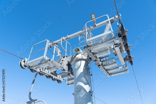 Ski chair lift over blue sky. Ski lift empty ropeway on hilghland mountain winter. Ski chairlift cable way with people enjoy skiing and snowboarding photo