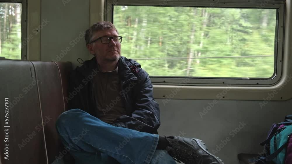 handsome unshaven middle-aged man rides in a commuter train car near the window and sleeps resting. transportation of people over long distances by public rail. slow motion. handsome unshaven middle-aged man rides in a commuter train car near the window and sleeps resting. transportation of people over long distances by public rail. slow motion.