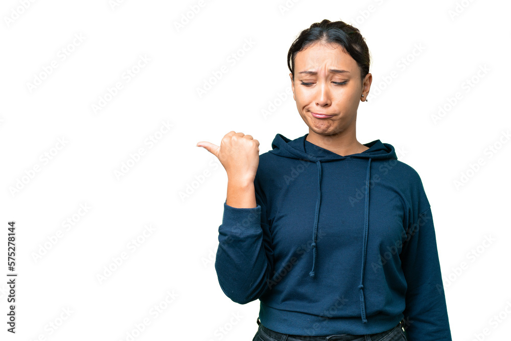 Young Uruguayan woman over isolated chroma key background unhappy and pointing to the side