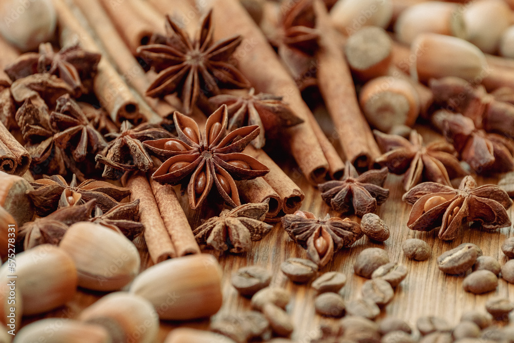 Background with cinnamon sticks, anise stars, coffee beans and nuts. Spicy trendy background. Close-up of various spices on wooden table top view