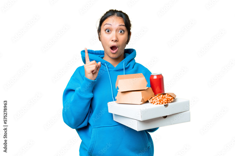 Young Uruguayan woman holding pizzas and burgers over isolated chroma key background intending to realizes the solution while lifting a finger up Young Uruguayan woman holding pizzas and burgers over isolated chroma key background intending to realizes the solution while lifting a finger up