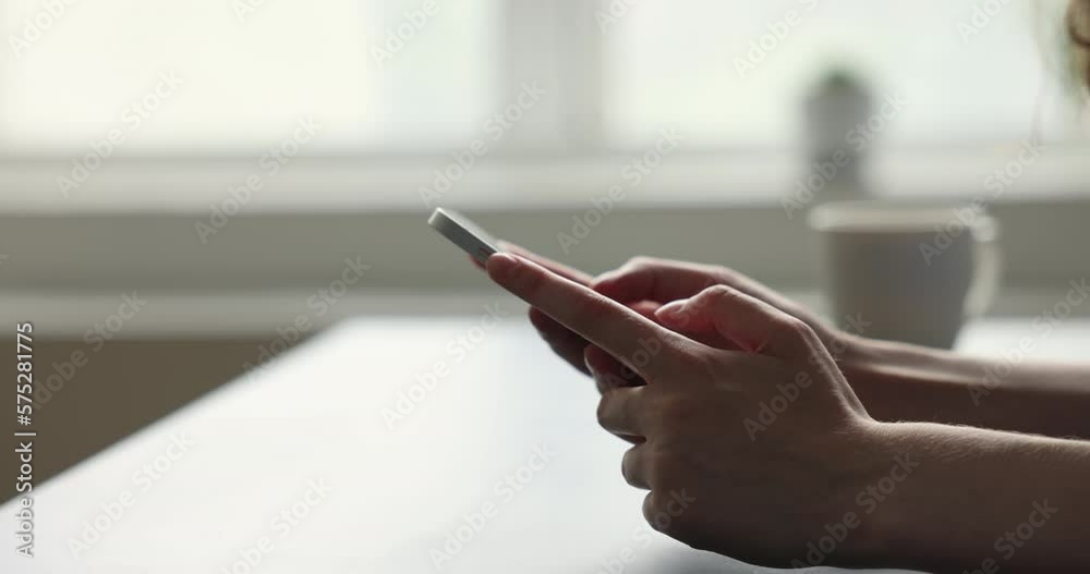 Hands of unknown female using modern smart phone seated at desk indoors, close up view. Sharing sms, messaging through messenger, mobile application usage for communication, spend leisure on internet Hands of unknown female using modern smart phone seated at desk indoors, close up view. Sharing sms, messaging through messenger, mobile application usage for communication, spend leisure on internet