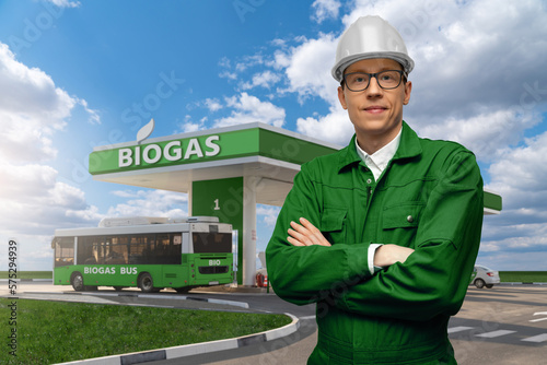 Engineer stands on a background of biogas filling station. Carbon neutral transportation concept	 photo