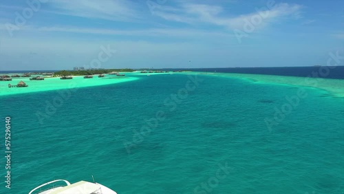 Aerial: Drone Forward Shot Of White Yacht Moored By Luxurious Resorts In Sea On Sunny Day - Thulusdhoo, Maldives photo