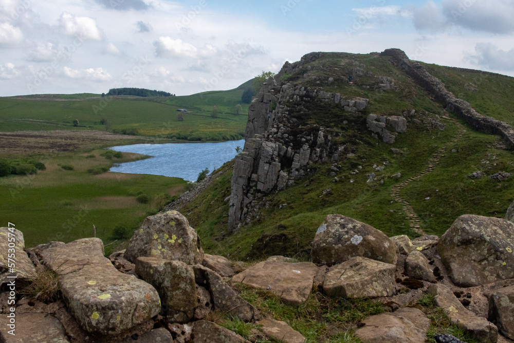 A stretch of Hadrian's Wall at milecastle 39 Roman military base, against backdrop of Whin Sill and Crag Lough lake in the distance. Northumberland National Park, UK