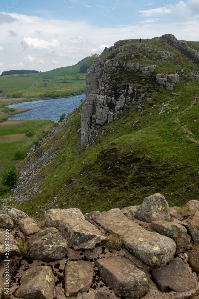 A stretch of Hadrian's Wall at milecastle 39 Roman military base, against backdrop of Whin Sill and Crag Lough lake in the distance. Northumberland National Park, UK