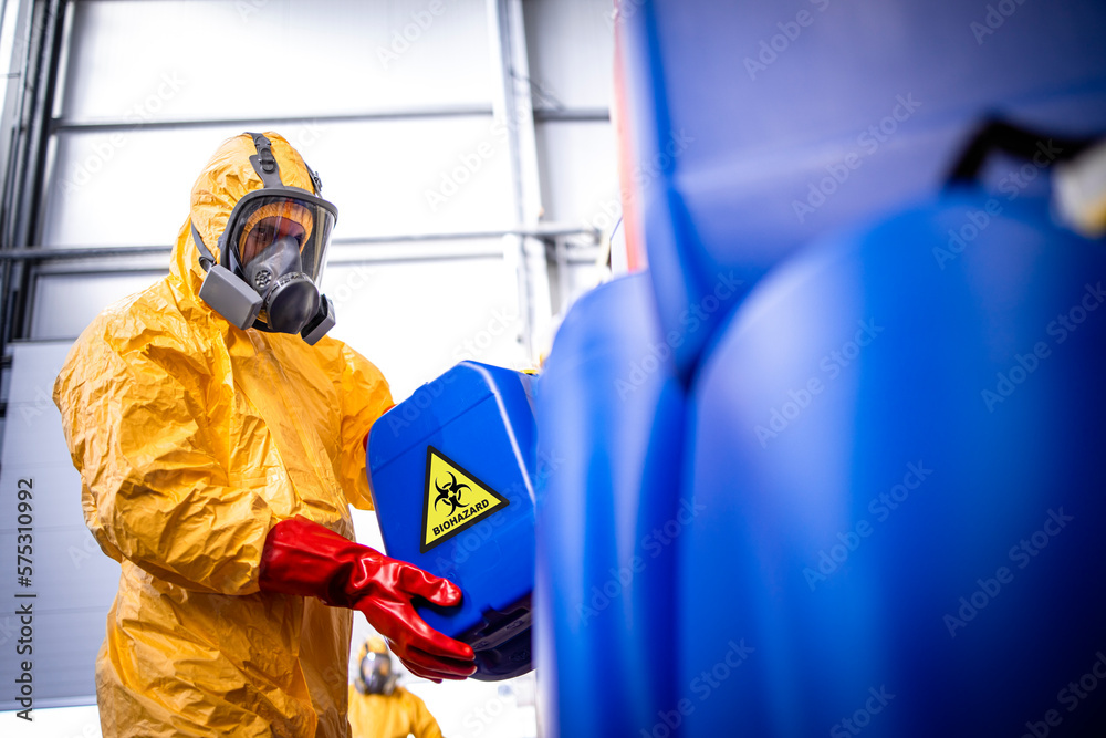 Factory worker with gas mask and protection suit working with toxic and dangerous chemicals.