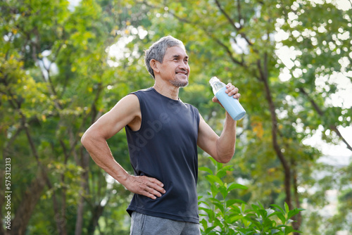 senior man drinking water after workout in the park for body refreshment, concept adult older drinking water substitutes while exercising