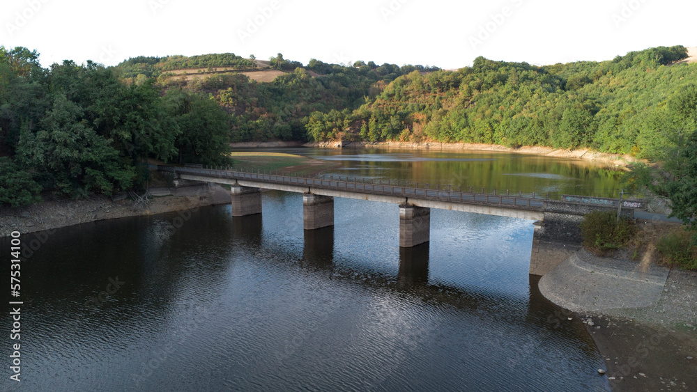Panoramic view of a bridge crossing a lake in summer, surrounded by the green forest and fields.