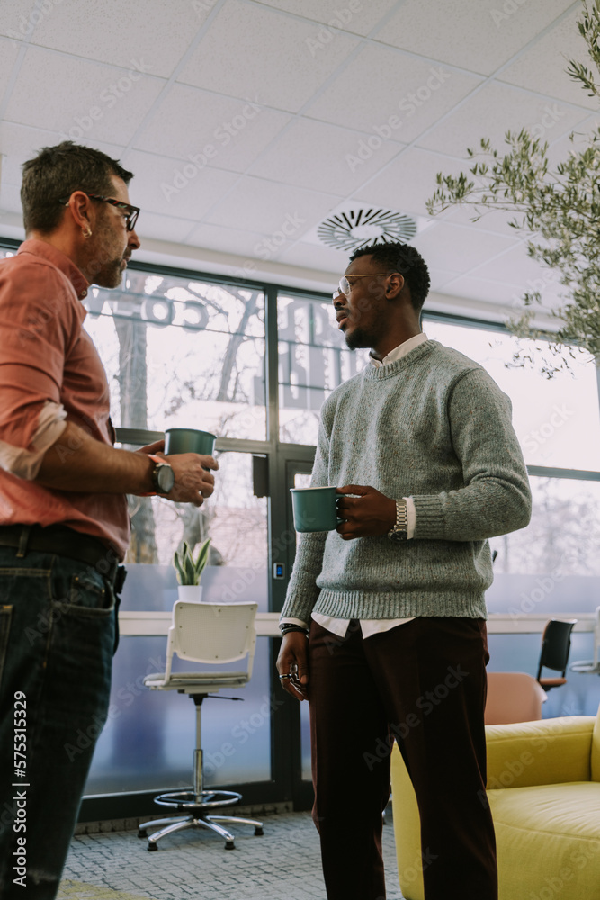 Fototapeta premium Two senior multiracial coworkers drinking coffee