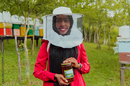 Portrait of a Muslim investitor in the beekeeping department of a honey farm holding a jar of honey in her hand photo
