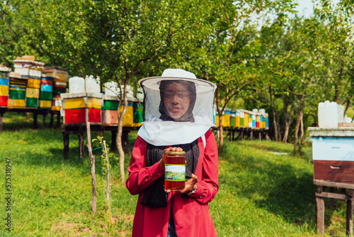 Portrait of Arab investitor in the beekeeping department of a honey farm holding a jar of honey in her hand photo