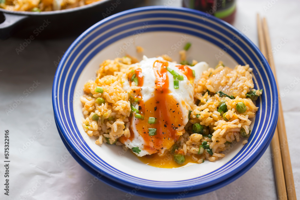 Kimchi fried rice with peas, fried egg and sriracha sauce Kimchi fried rice with peas, fried egg and sriracha sauce