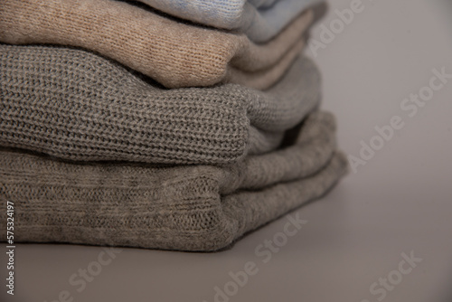 Stack of folded knitted sweaters close-up isolated on white background