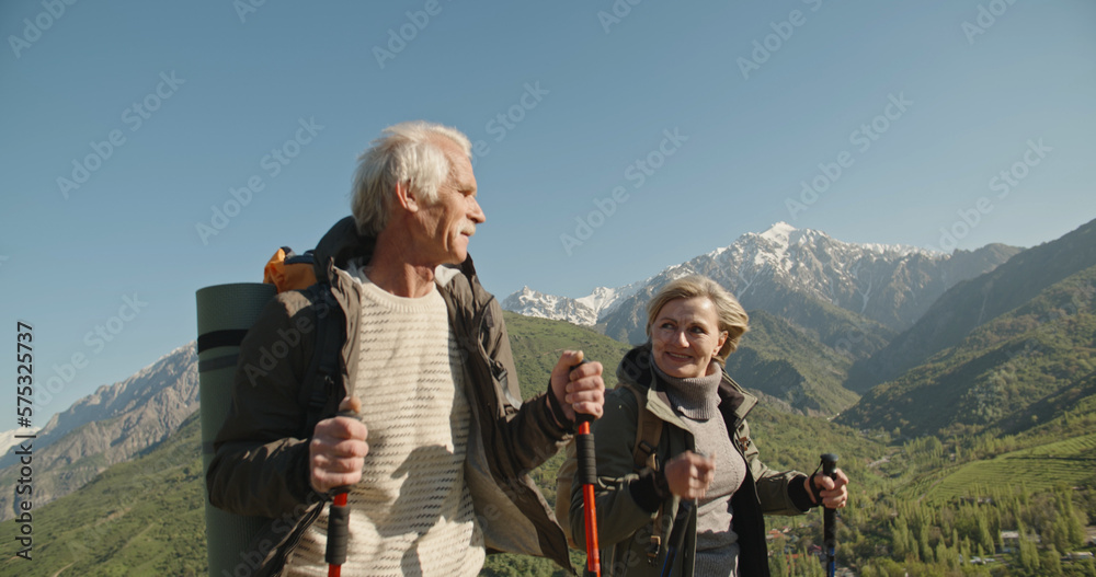 Senior tourist couple travellers hiking in nature, walking and talking.