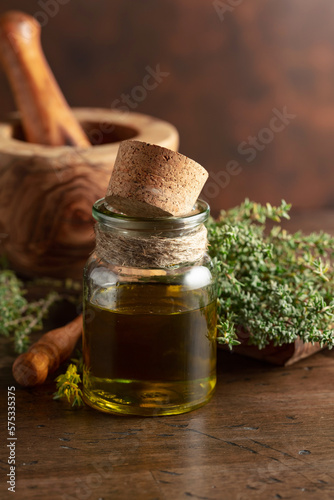 Bottle of thyme essential oil with fresh thyme.
