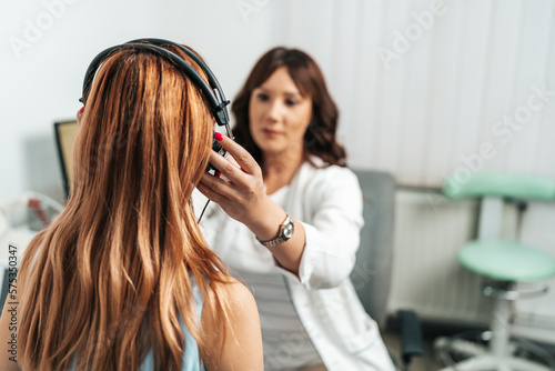 Audiologist doing impedance audiometry or diagnosis of hearing impairment. An beautiful redhead adult woman getting an auditory test at a hearing clinic. photo