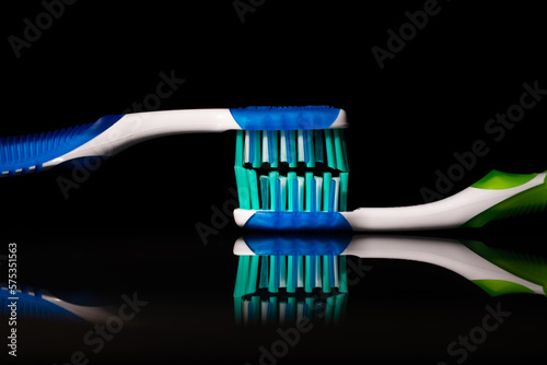 Two toothbrushes on an isolated black background with a mirror reflection. Free space for text. Close-up macro.