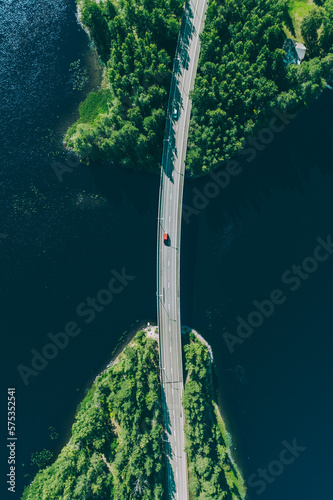 Aerial view of bridge road through blue lakes with green woods in Finland.