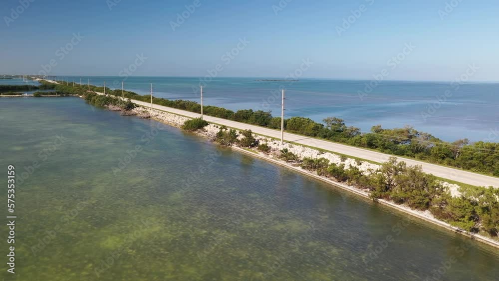 Car traveling along Florida Keys US1 road with ocean on both sides and power lines. Car traveling along Florida Keys US1 road with ocean on both sides and power lines.