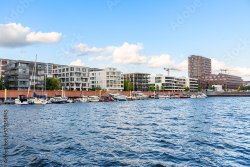 Modern apartment buildings along a river harbour on a clear summer evening © alpegor