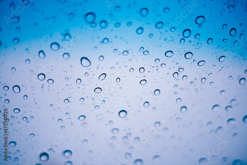 Blue water droplets and raindrops cling to the cool clear glass