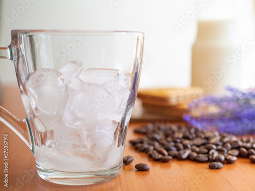 a glass of ice and coffee beans on a table, Cookies and milk bottle on background