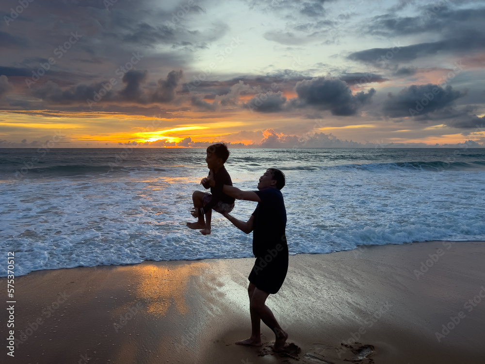 Father and son playing on the beach in the evening