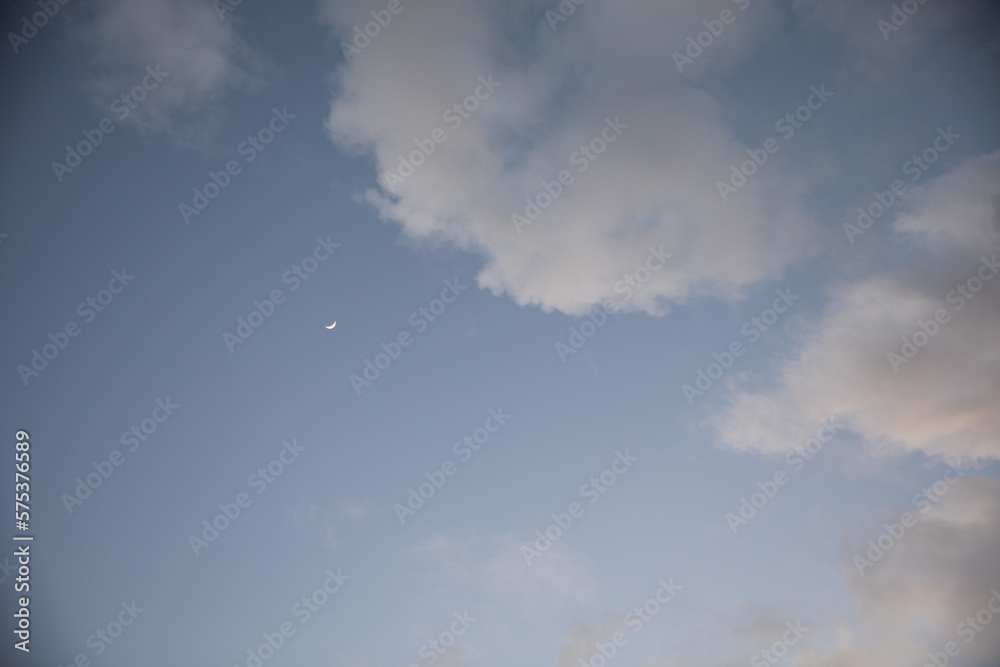 crescent moon in the evening sky by clouds soft lighting during dawn crescent moon in the evening sky by clouds soft lighting during dawn